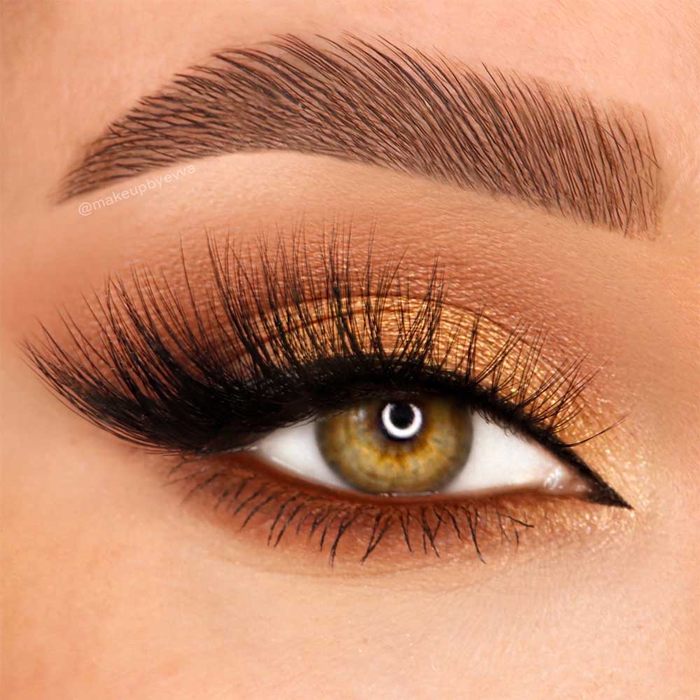 A close-up of a hazel eye enhanced by glamnetic Vibe vegan synthetic fiber magnetic lashes, golden-brown eyeshadow, precise black eyeliner, and a bold, well-groomed eyebrow. - Product image