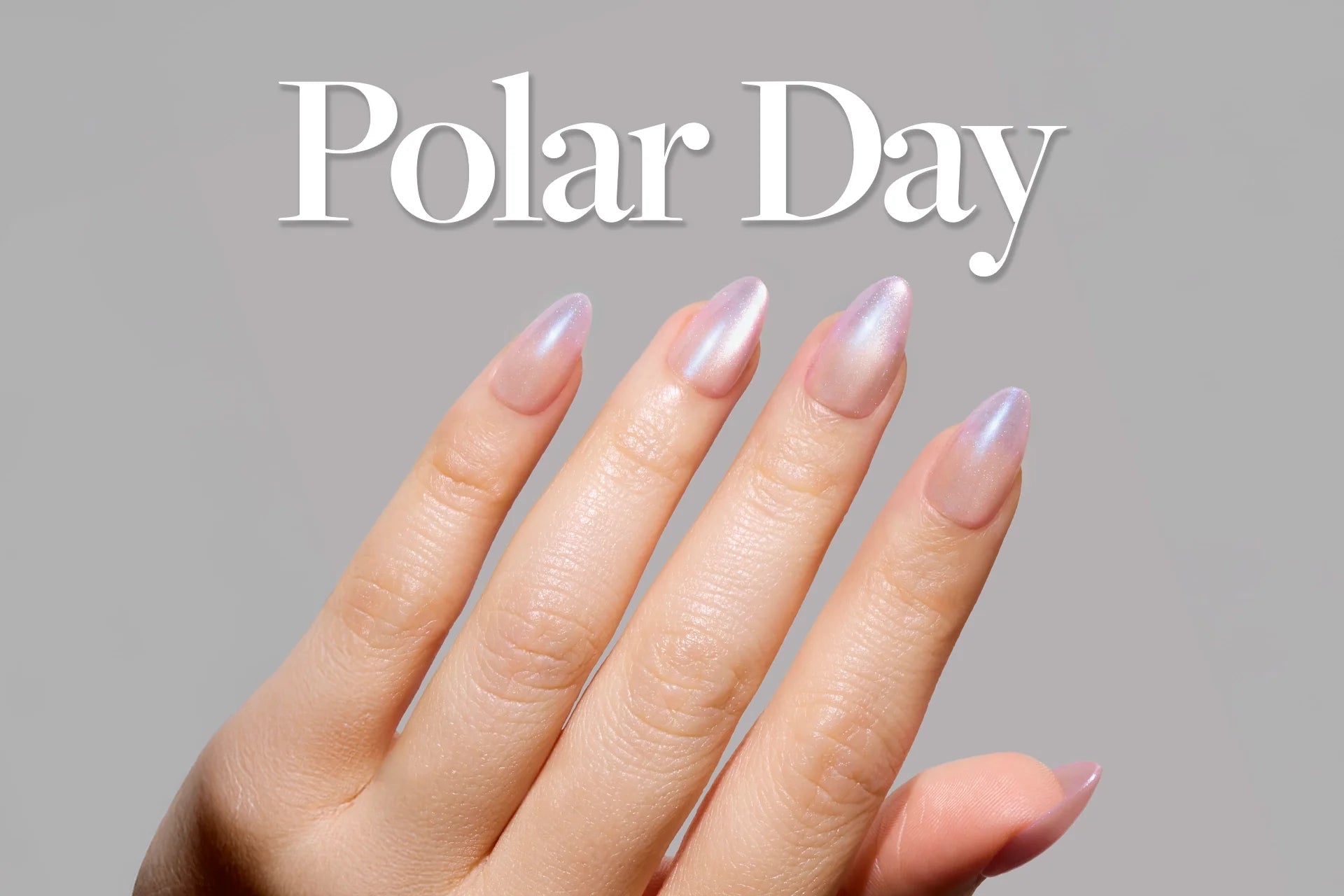 Close-up of a hand with long almond-shaped nails in an iridescent icy-pink shade, with the text ‘Polar Day’ displayed above on a soft grey background.