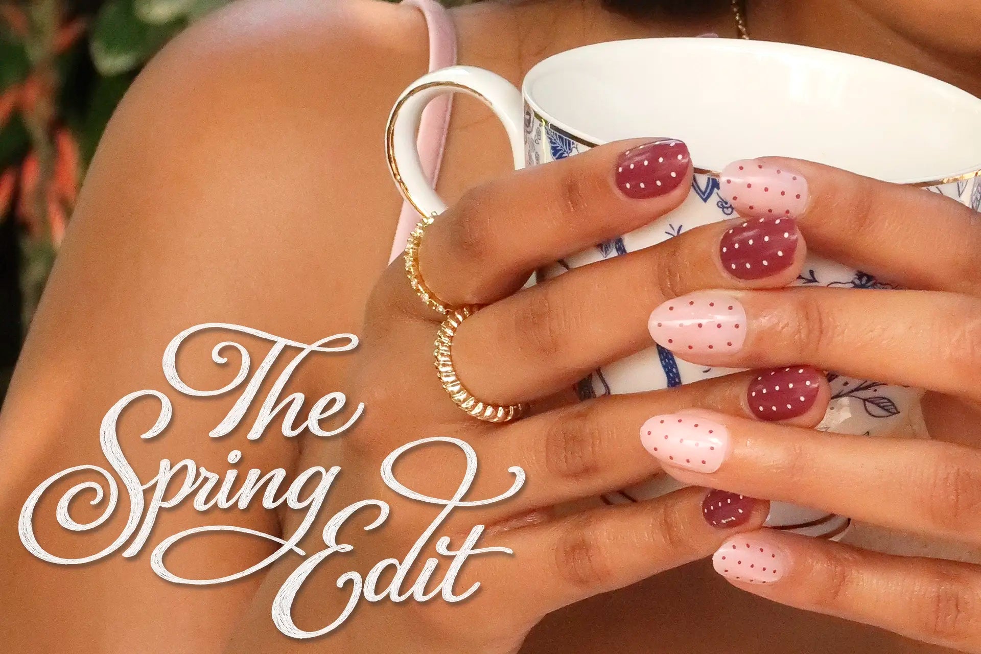 Hands holding a teacup with pink and red polka dot press-on nails, “The Spring Edit” text overlay.