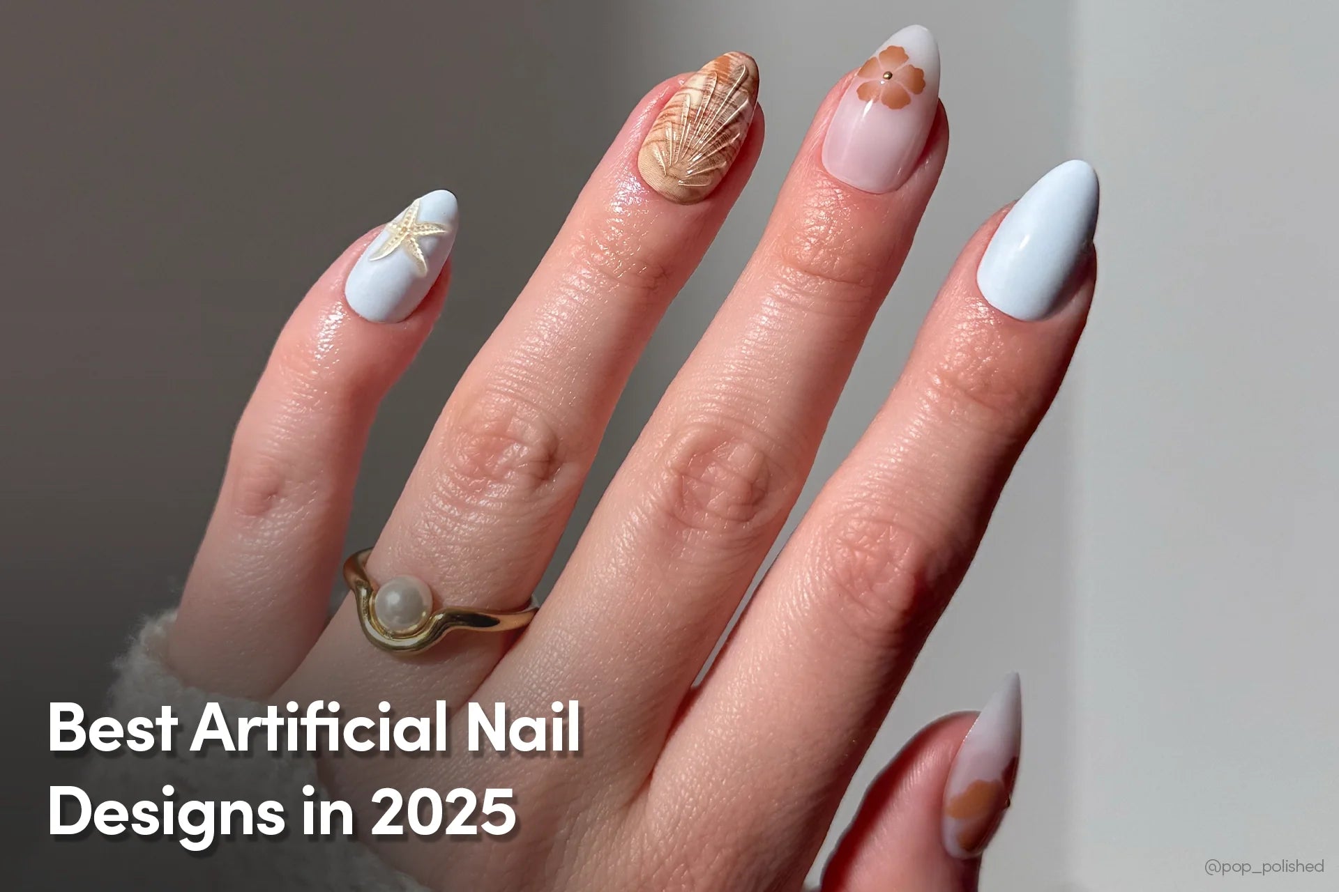 Hand showcasing a variety of pastel and neutral-toned nail art, including starfish, seashell, and floral designs, accessorized with a gold ring featuring a pearl.