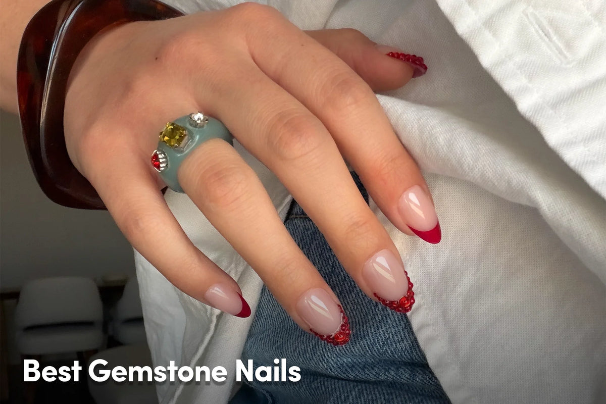 Red French tip nails with gemstone accents.