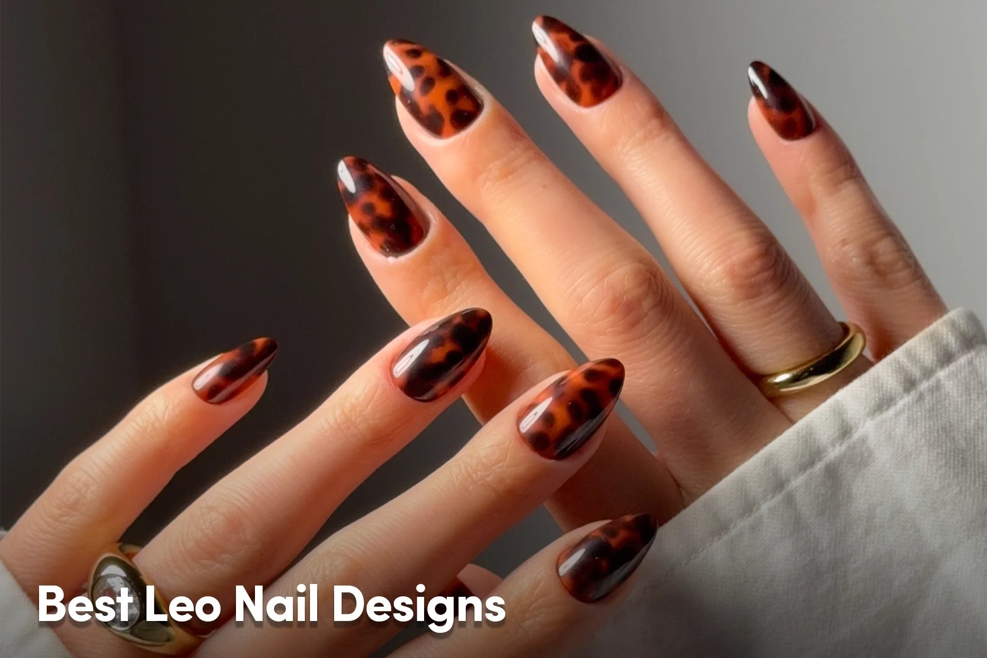 Glossy tortoiseshell almond nails in warm amber and dark brown tones.