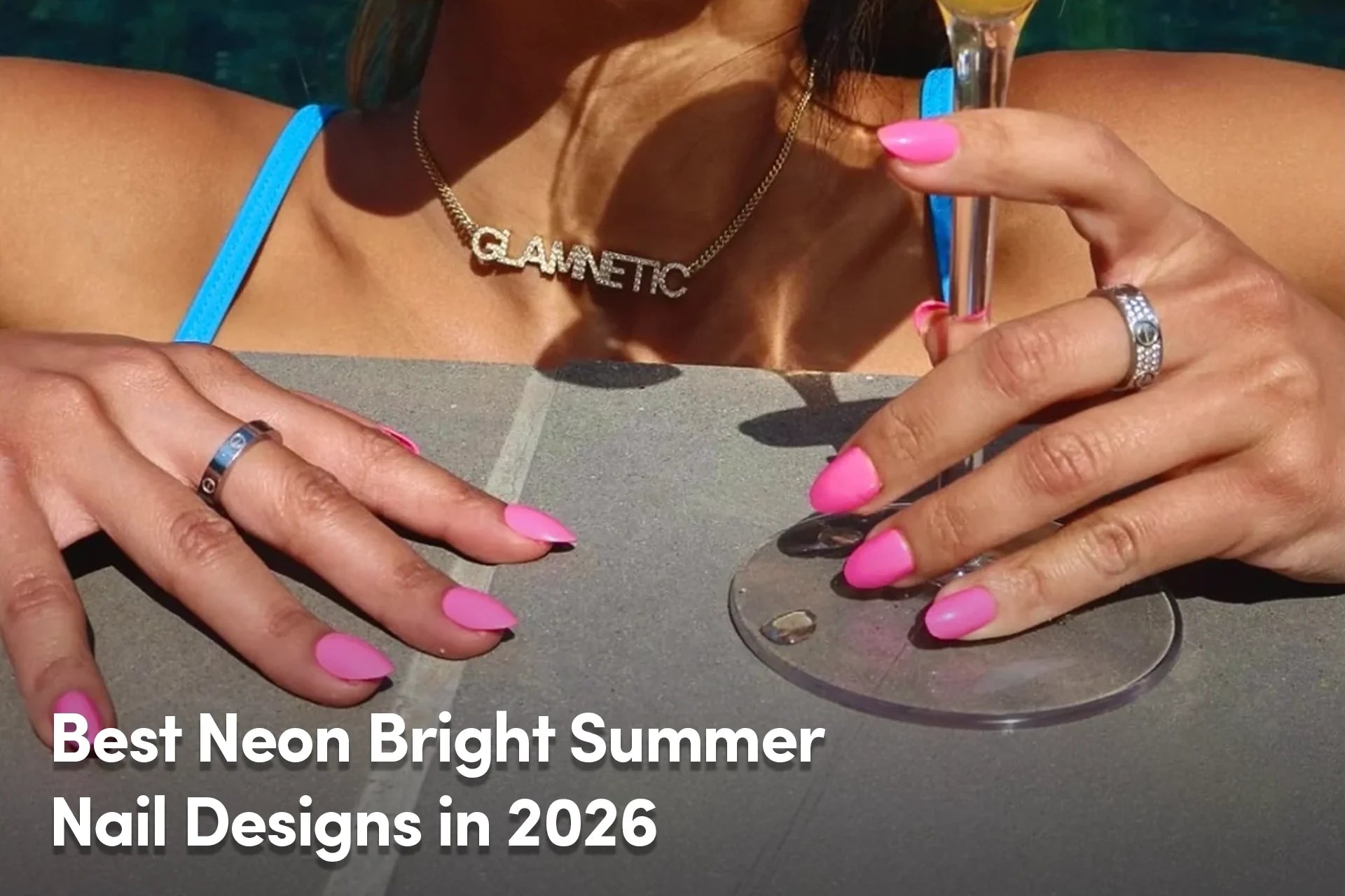 Neon pink summer nails with a cocktail by the pool.