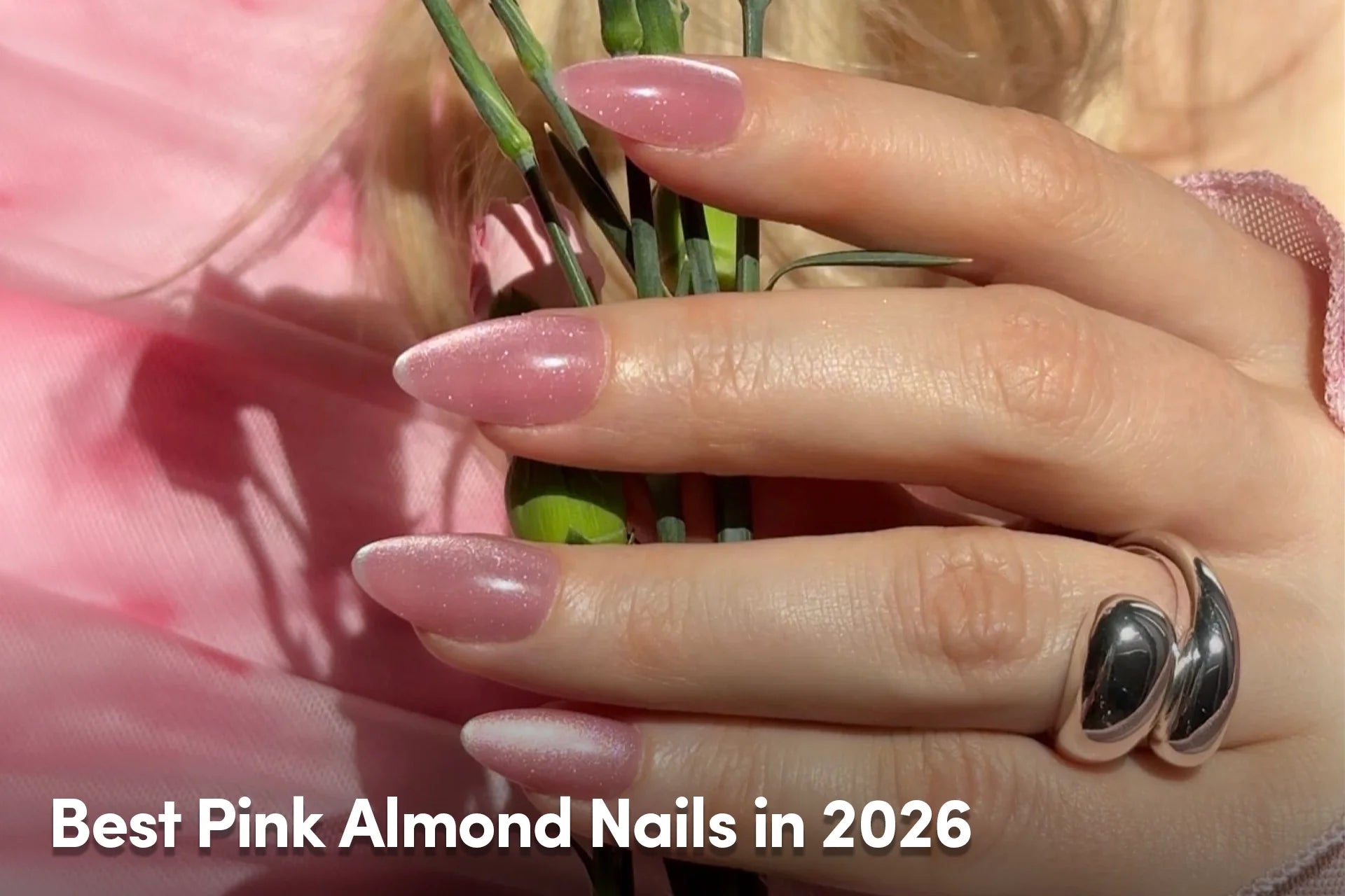 Hand with soft pink almond-shaped nails with a subtle shimmer finish.