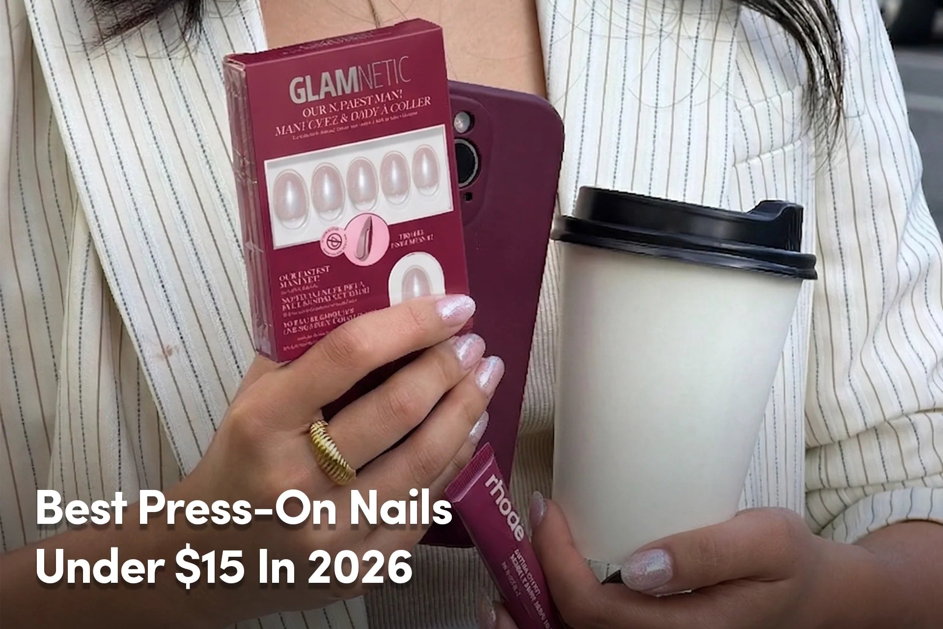 Person holding Glamnetic press-on nails, phone, and coffee cup.