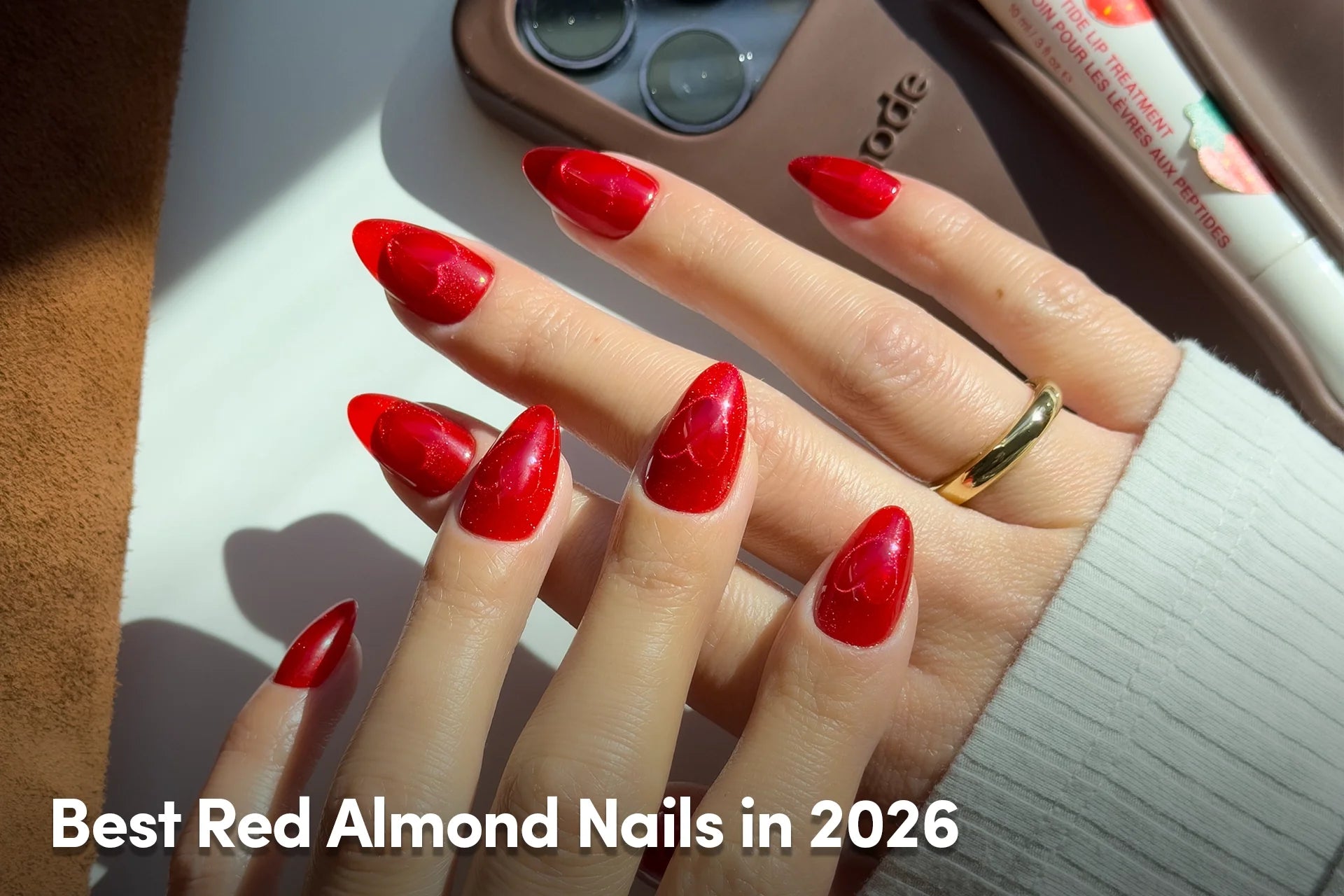 Hand with glossy bright red almond-shaped nails in sunlight.