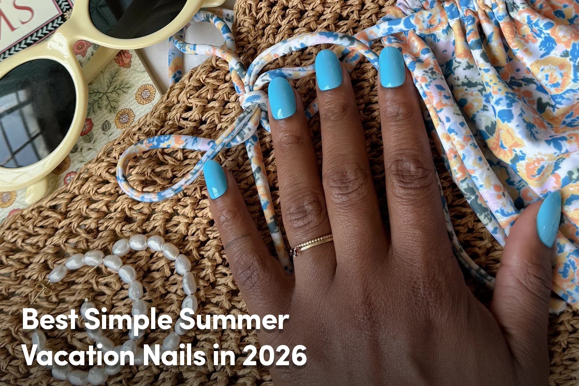 Bright blue summer nails styled with floral vacation accessories.