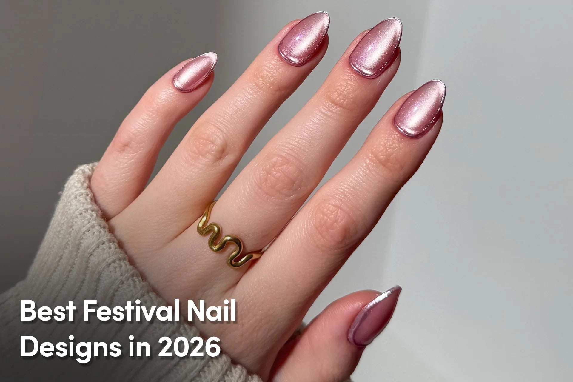 Shimmery pink chrome almond-shaped nails on hand with gold ring
