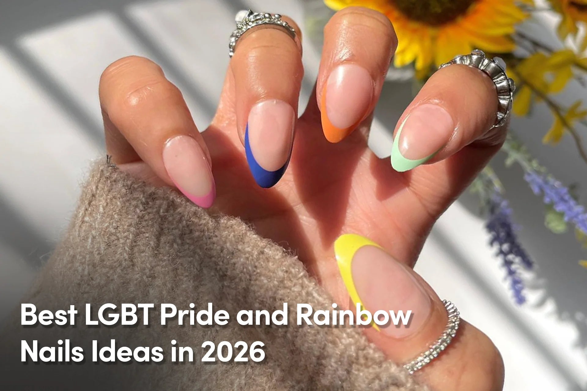 Almond-shaped nude nails with colorful rainbow French tip accents.