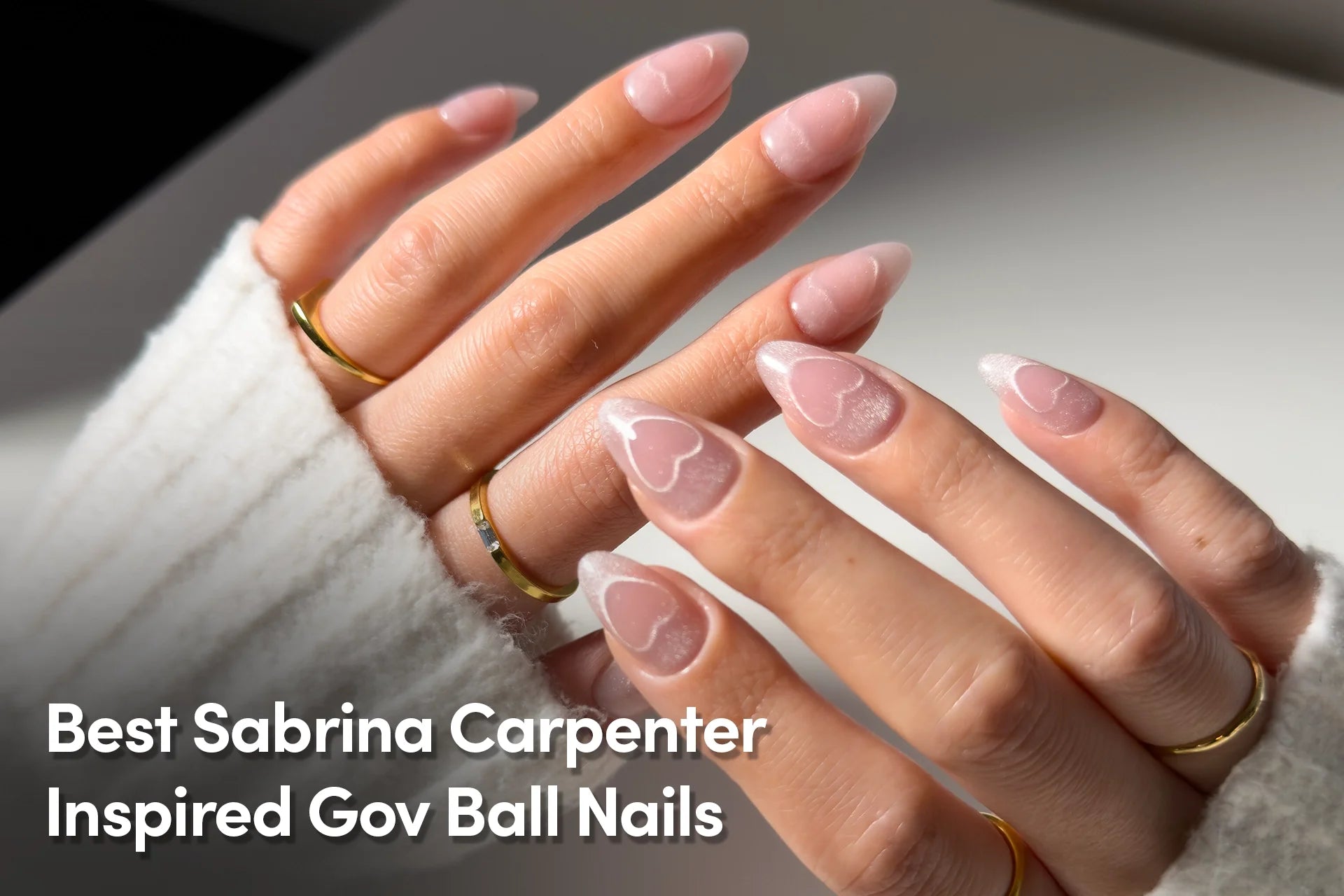 Shimmering pink almond-shaped nails with delicate white heart accents, inspired by Sabrina Carpenter’s Gov Ball style.
