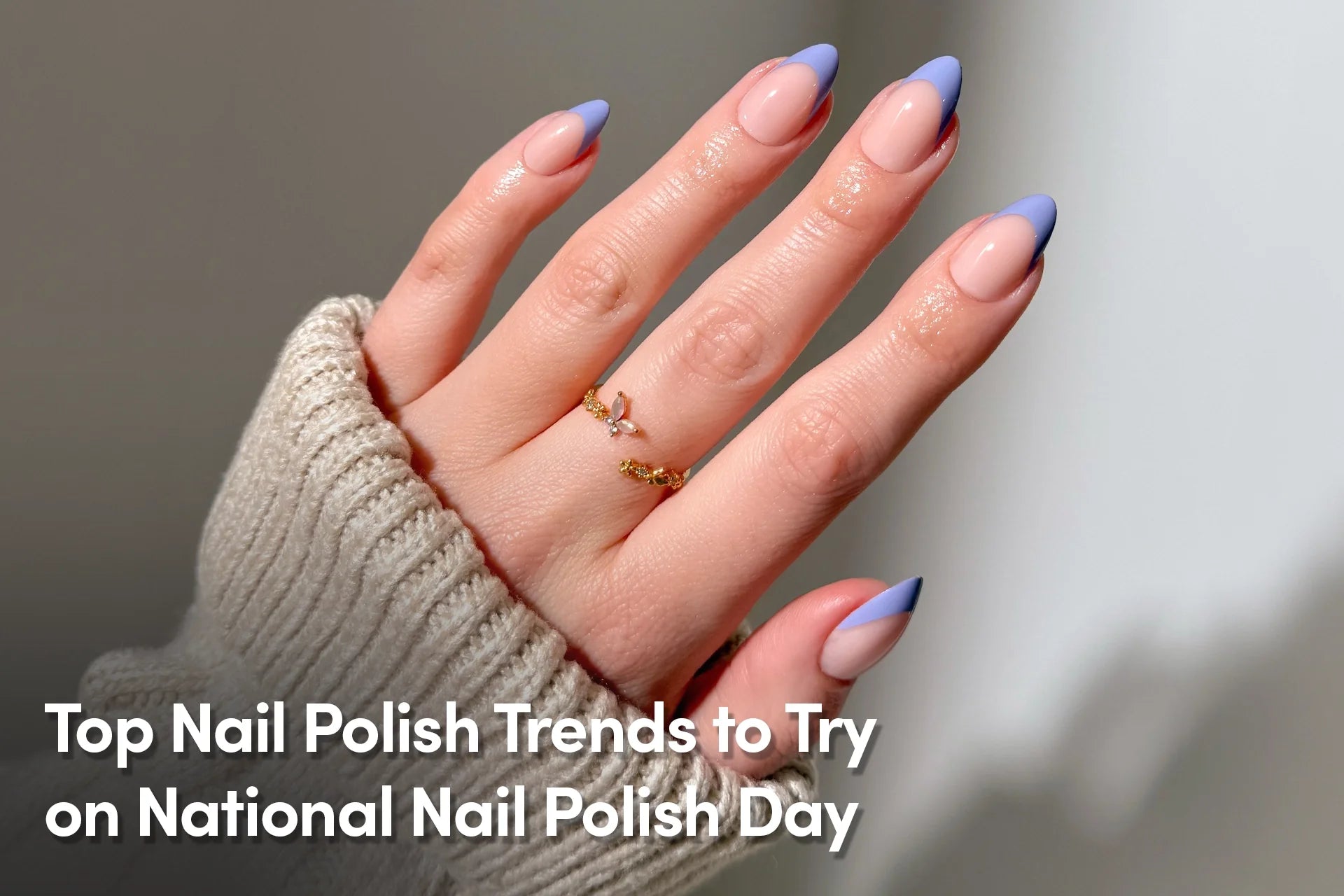 Hand with glossy nude nails and soft periwinkle French tips, showcasing a modern nail polish trend.