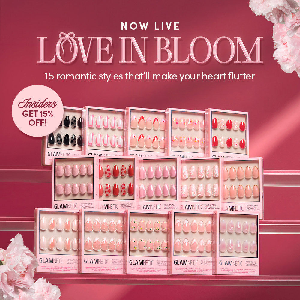 A display of Glamnetic press-on nails in romantic pink and red designs under the text Love in Bloom, promoting 15 styles with a 15% off offer for insiders. Pink flowers frame the image.