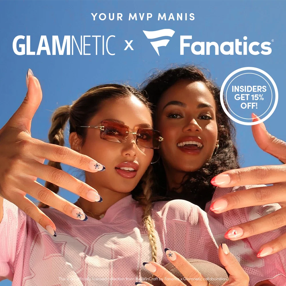 Two women show off manicured nails with sports-themed designs under a blue sky. The image promotes a Glamnetic x Fanatics collaboration with a 15% off offer for insiders.