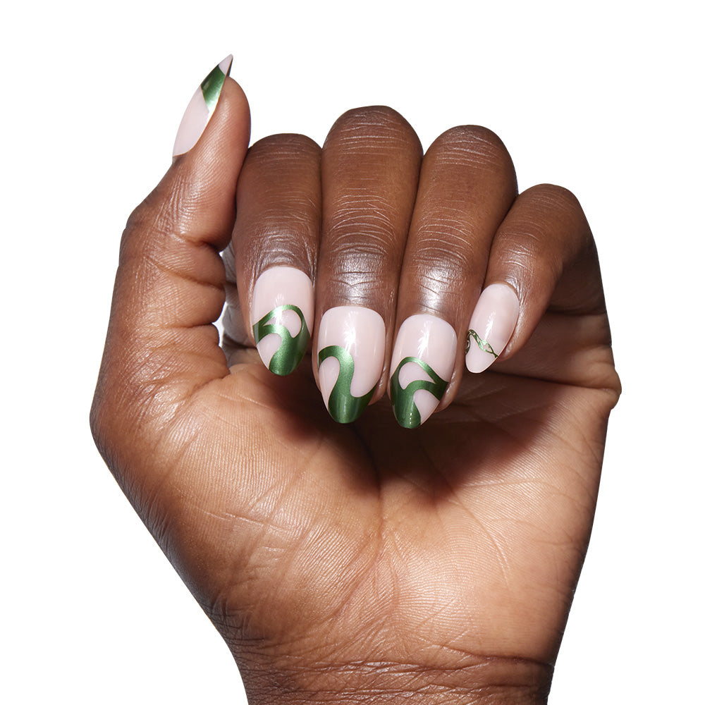 A hand with short almond-shaped nails in glamnetic’s Parseltongue™—an emerald chrome swirl design on a nude base—shown against a white background. - Product image