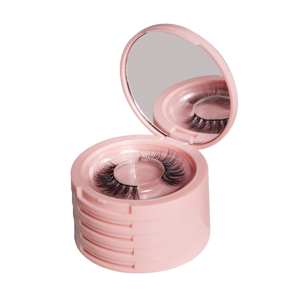 The glamnetic Glam &amp; Go Travel Case is a pink circular container with a built-in mirror, holding several pairs of Glamnetic Lash Extensions in separate compartments. The open case displays one set of magnetic lashes and the mirror.