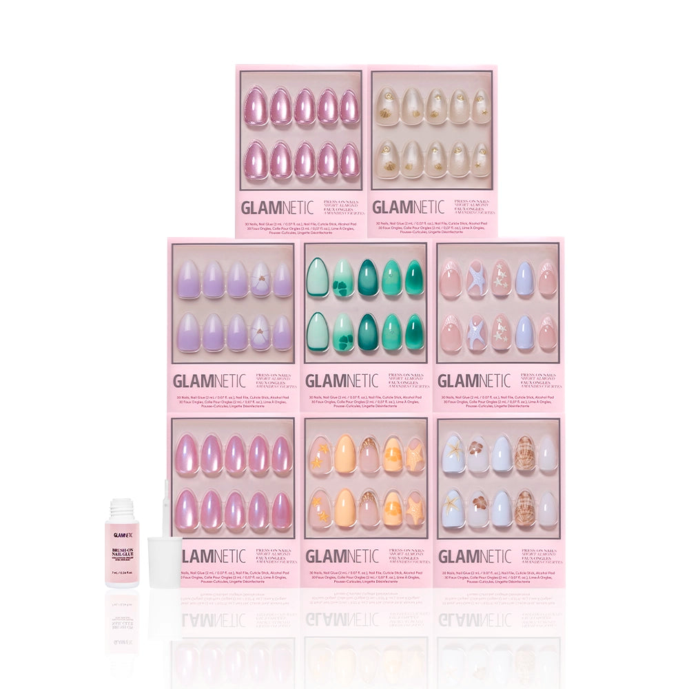 Eight Glamnetic press-on nail boxes, including the Almonds At Sea set, are stacked in a pyramid. A small nail glue bottle is on the left. The scene has a white background. - Product image