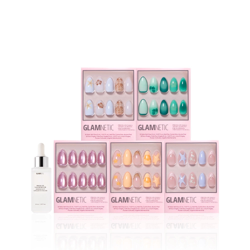 Five sets of glamnetic Ann’s Cove press-on nails in pink boxes, showcasing colorful and 3D nail art designs, are arranged in two rows. A white dropper bottle sits to the left of the display. - Product image