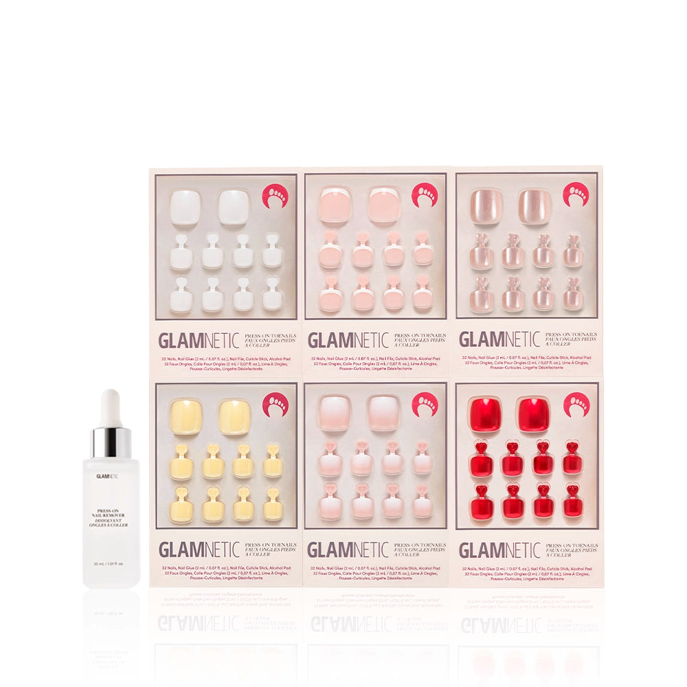 Glamnetic Glazed & Glossy Pedi Bundle shown with a white dropper bottle of press-on nail remover. The six press-on toenail kits are arranged in two rows, showcasing a mix of nude, shimmer, pastel, and bold red hues - Product image