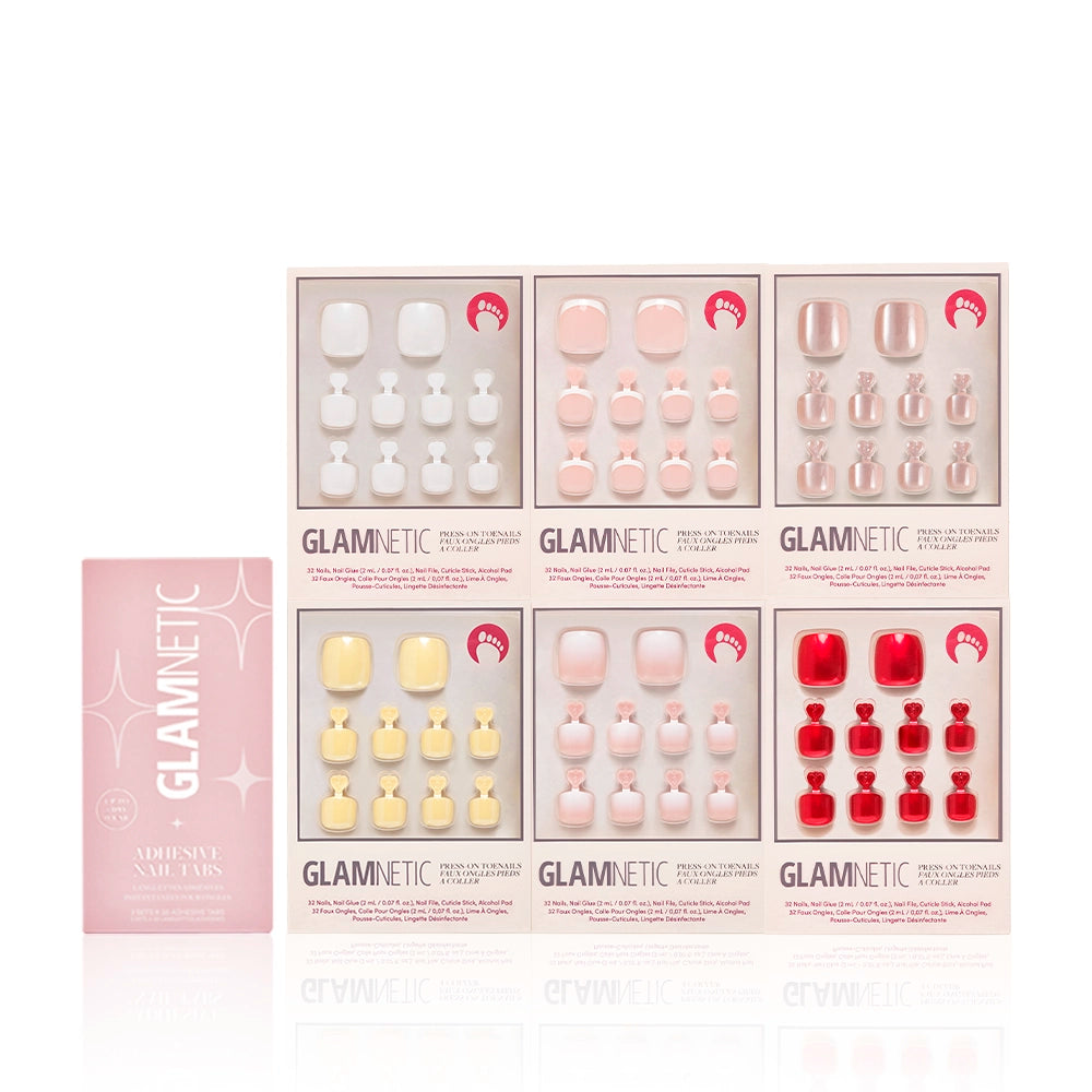 Glamnetic Glazed & Glossy Pedi Bundle displayed with a pink box of adhesive nail tabs. The bundle includes six coordinated press-on toenail sets in varying finishes from natural to bold, all neatly packaged. - Product image