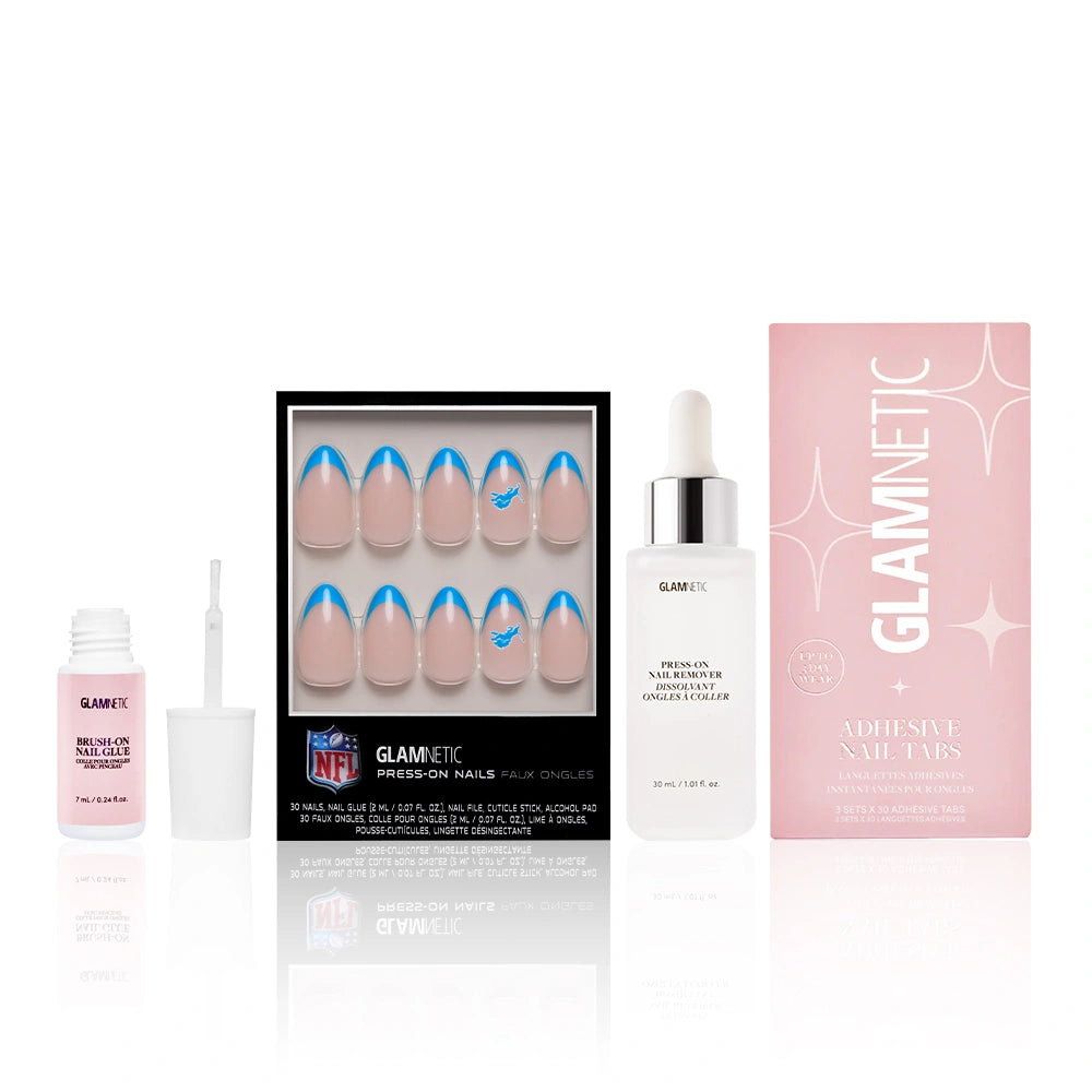 The Detroit Lions Press-On Playbook by glamnetic includes blue Lions-themed French tip press-on nails, a pink nail glue bottle, Press-on nail remover, and adhesive tabs—all officially licensed by the team.