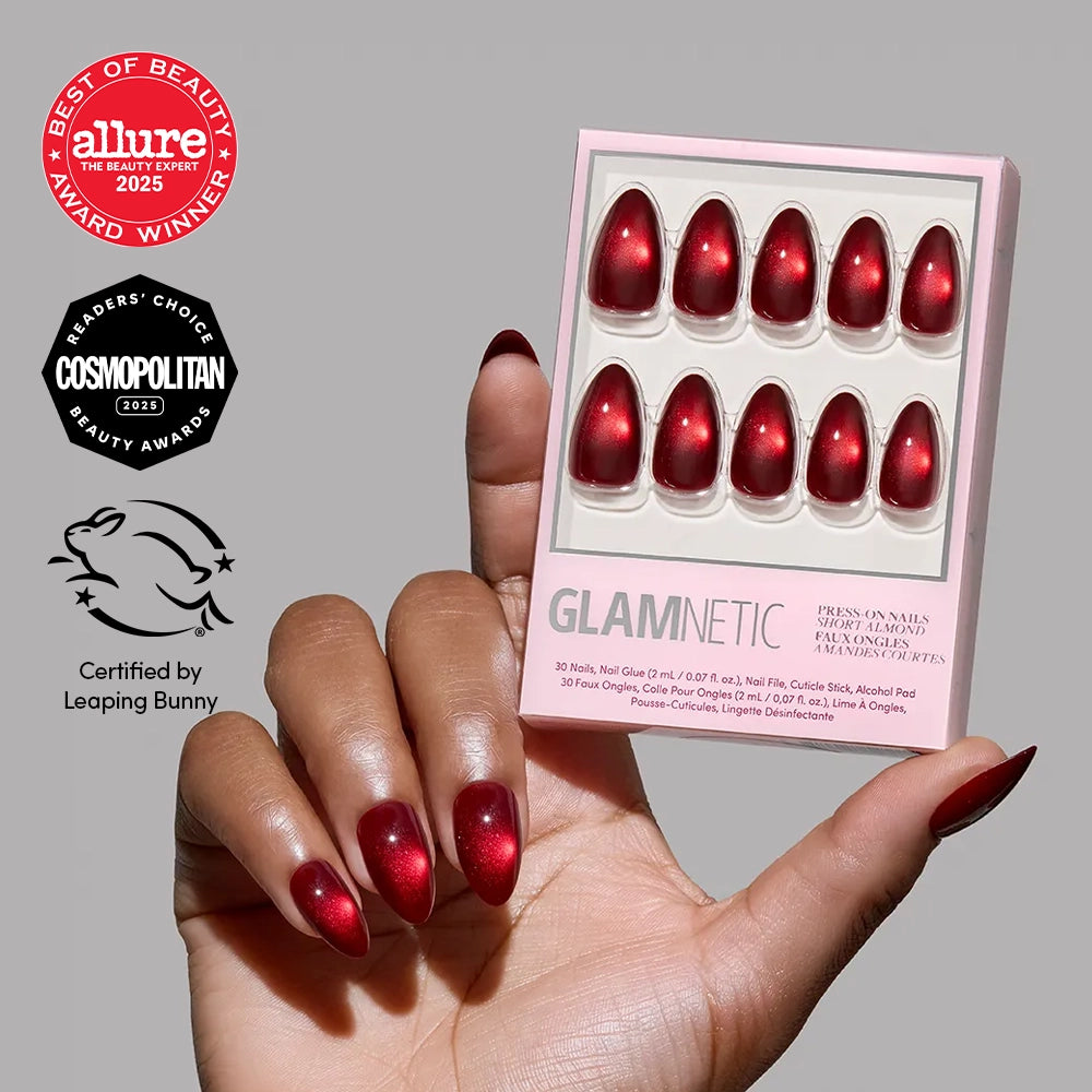 A hand with short almond-shaped red magnetic cat-eye nails holds a matching Frosted Cranberry nail set, accompanied by Allure and Cosmopolitan award logos and a Leaping Bunny certification.