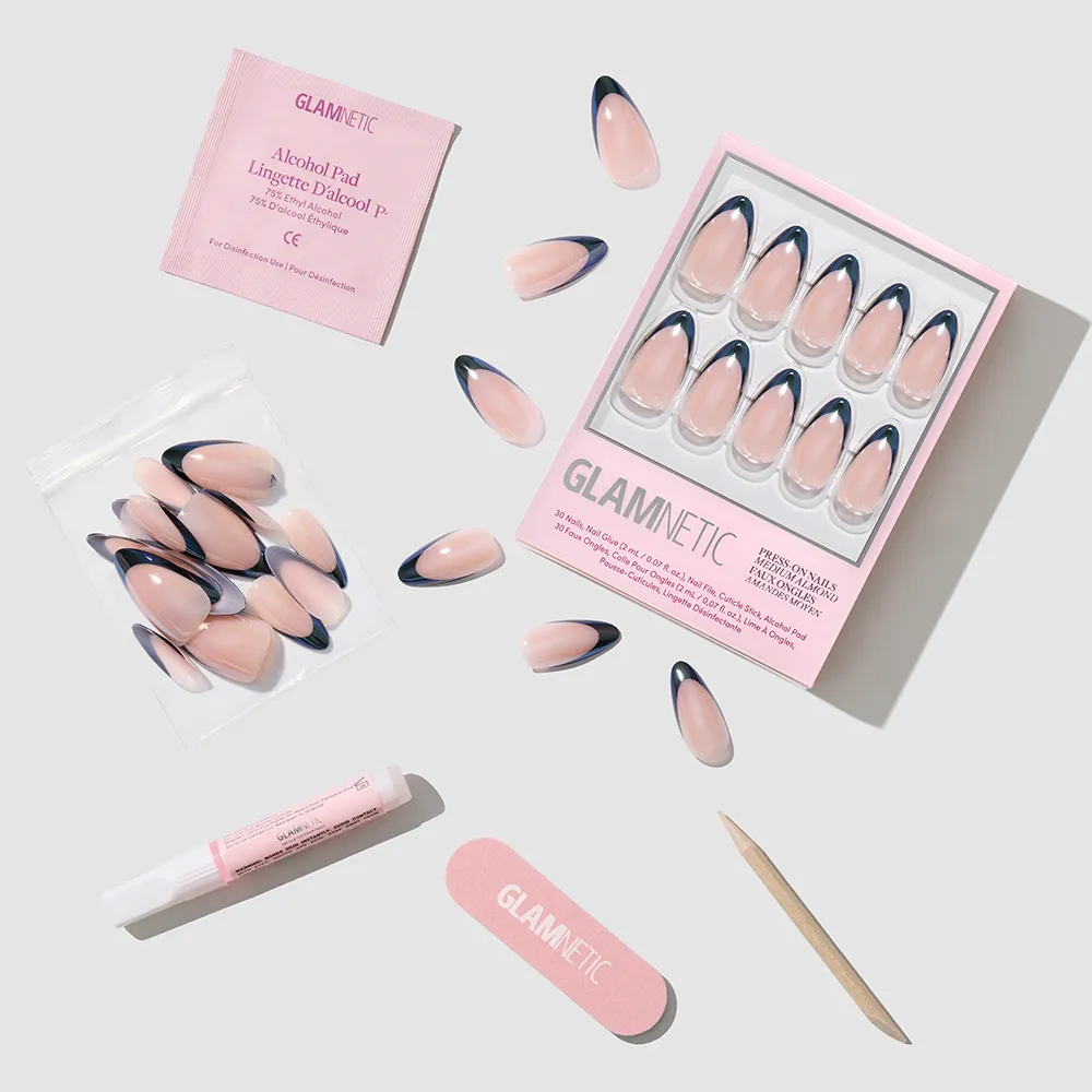 Black Truffle by glamnetic: almond-shaped pink and navy blue press-on nails with French tips, plus alcohol pad, glue tube, nail file, cuticle stick, and extra nails—all arranged neatly on a light gray background. - Product image