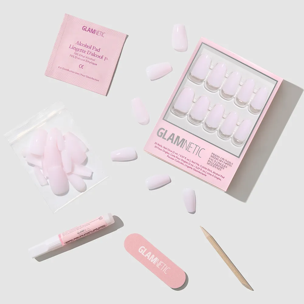 A glamnetic Blush Dream press-on nails kit features soft pink medium coffin nails, a nail file, cuticle stick, nail glue, alcohol pad, and extra nails arranged on a light gray background. - Product image