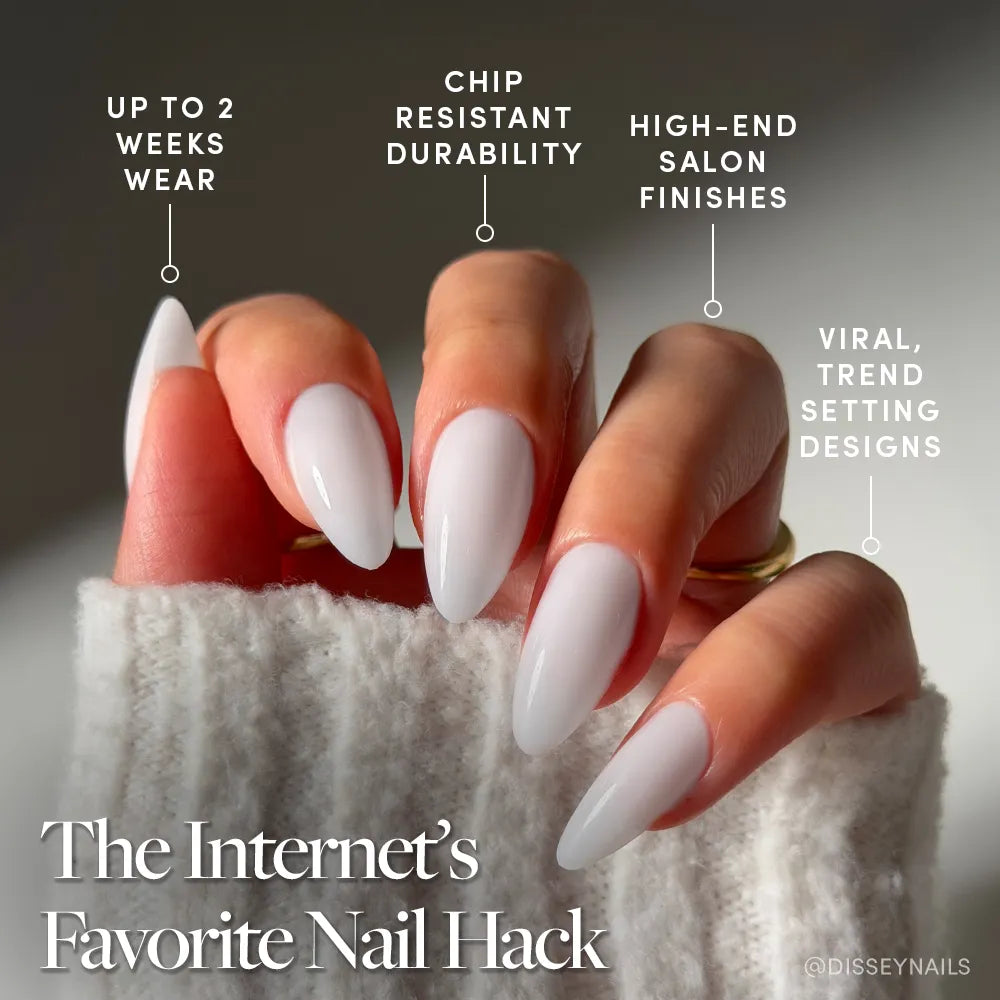A hand with long, almond-shaped nails wears "Clouded" by glamnetic—a milky pale grey mani. Text highlights up to 2 weeks wear, chip-resistant durability, salon finish, and viral trendsetting design. A sweater sleeve partly covers the hand. - Product image