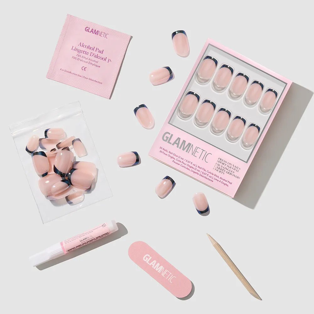 The glamnetic Squid Ink Press-On Nails feature a light pink base, dark French tips, and glazed finish. The set includes a nail file, cuticle stick, glue, alcohol pad, and extra nails on a light gray background. - Product image