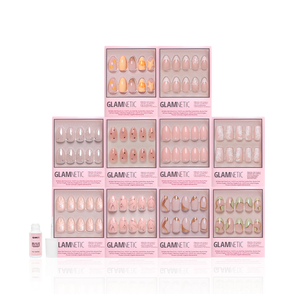 Ten boxes of glamnetic's "It's Giving More Dimension" press-on nails, with short almond 3D nude and pink designs, are stacked in a pyramid. A small bottle of nail glue is placed to the left, all set against a white background. - Product image
