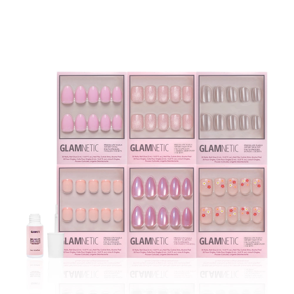Six boxes of glamnetic's Pink Intentions salon-quality press-on nails, featuring floral and short designs, are arranged in two rows with a small nail glue bottle positioned at the bottom left in front of the boxes. - Product image
