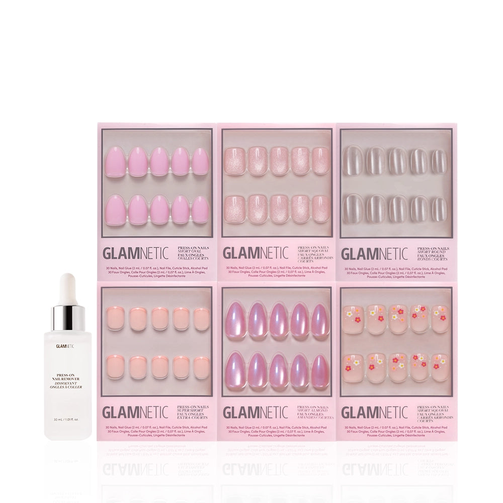 Six boxes of glamnetic Pink Intentions press-on nails in assorted nude styles, including solid, glossy, glitter, and floral designs, are arranged in two rows. A glamnetic cuticle oil bottle is placed in front for a polished finish. - Product image