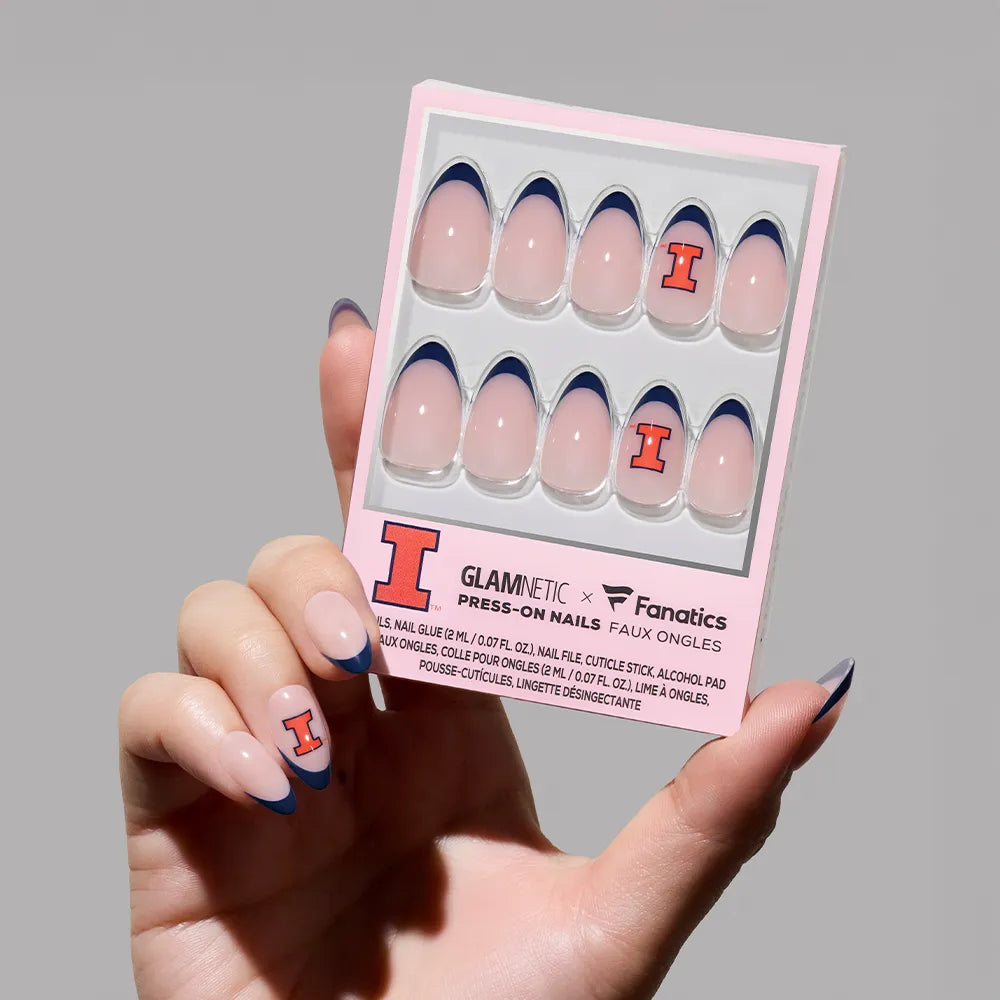 A hand displays the glamnetic Illinois Fighting Illini Press-On Nail Set, featuring pink nails with blue French tips and an orange "I" accent. The thumb also shows the bold "I" for team spirit. - Product image