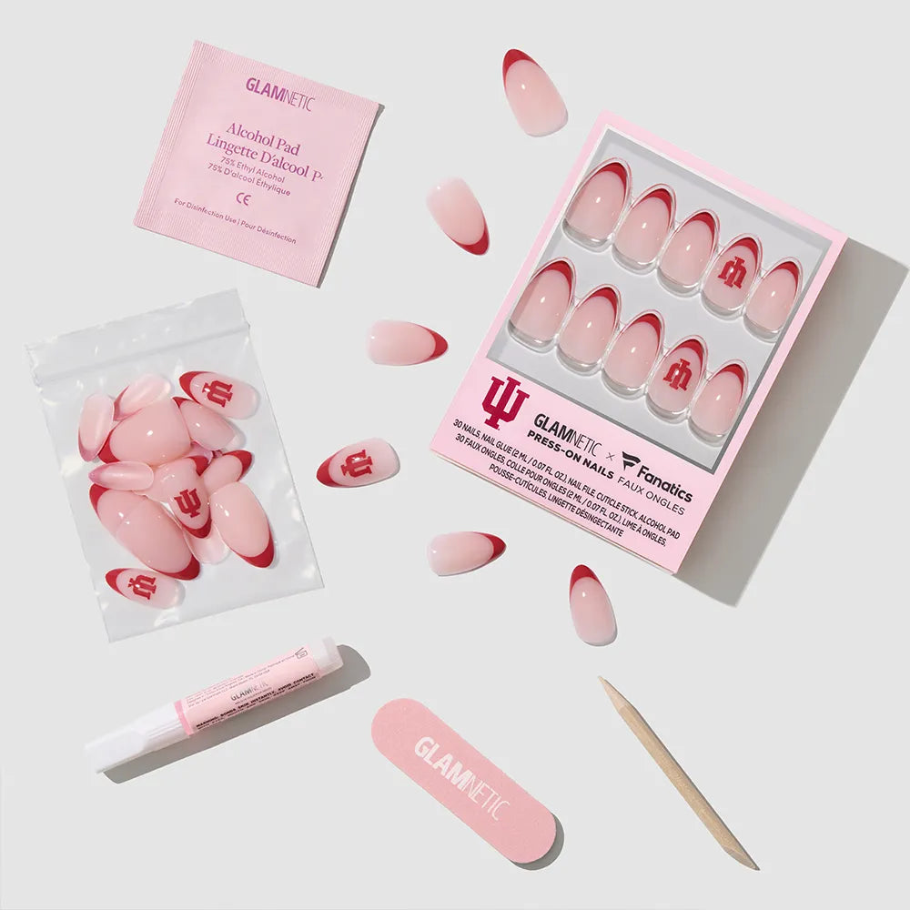The glamnetic Indiana Hoosiers Press-On Nail Set includes pink and red nails, nail glue, an alcohol pad, nail file, wooden cuticle stick, and extra nails, all displayed on a white background. - Product image