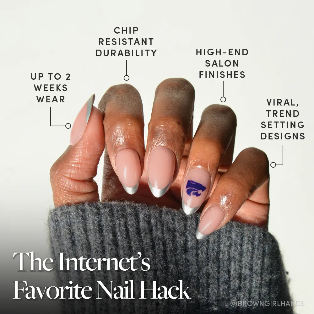 A hand with neatly manicured glamnetic Kansas State Wildcats Press-On Nails, featuring French tips and a purple Wildcats logo accent. Enjoy up to 2 weeks wear, chip resistance, salon finish, and trendsetting designs. Sweater sleeve partially covers the hand. - Product image