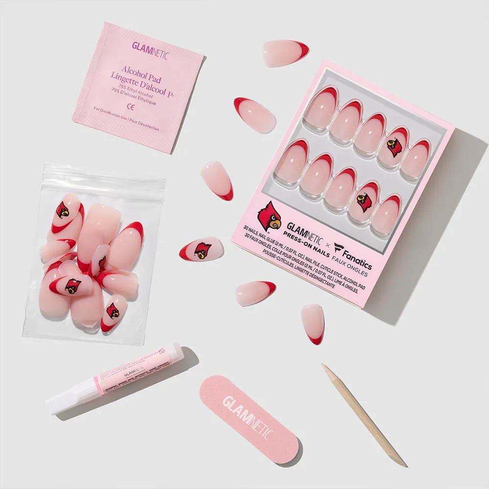 The glamnetic University of Louisville Cardinals Press-On Nail Set includes pink and red nails with the team’s bird logo, a pink nail file, wooden cuticle stick, glue tube, alcohol pad in pink packaging, and extra nails on a white background. - Product image