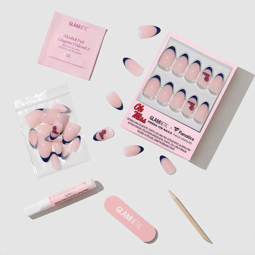 The glamnetic Mississippi Rebels Press-On Nail Set features pink nails with dark blue tips and comes with salon-quality nails, nail glue, a cuticle stick, nail file, alcohol pad, and extra nails—all arranged on a light surface. - Product image