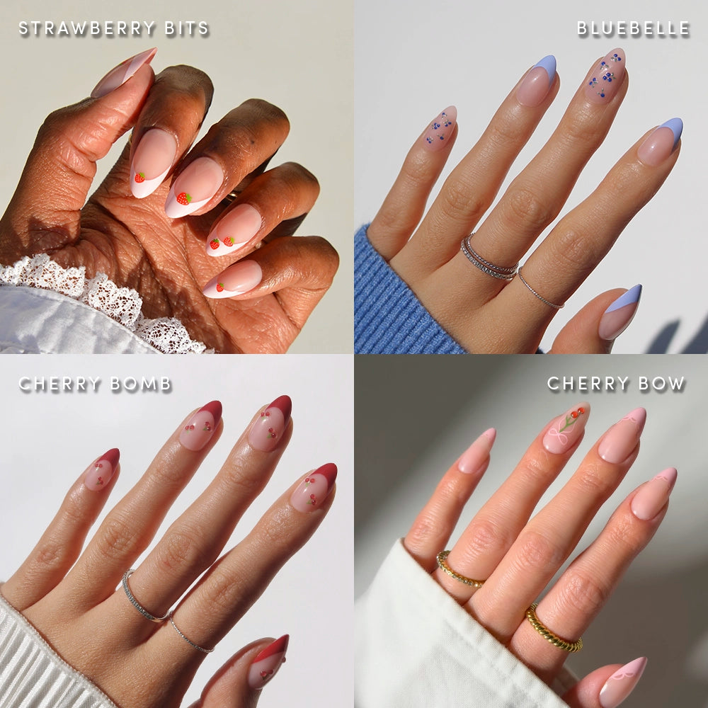 A collage of four manicured hands features the glamnetic Fruit Stand Faves set, showcasing almond nails with berry accents, blue French tips with dots, red tips with cherries, and pink nails with tiny bows.