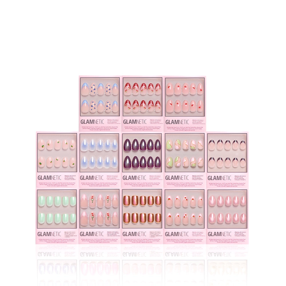 Twelve boxes of glamnetic’s The Juicy Drop Collection, showcasing glossy press-on nails with unique designs, are arranged in a pyramid formation against a white background. - Product image