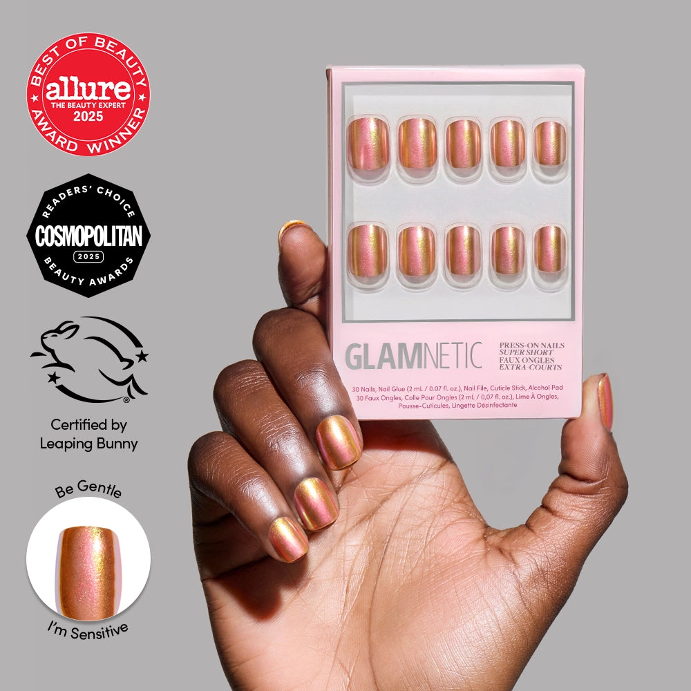 A hand with metallic peach Papaya Chrome press-on nails holds a box of matching glamnetic nails. Award badges for Allure 2025, Cosmopolitan 2023, vegan, cruelty-free, and sensitivity-friendly are displayed.