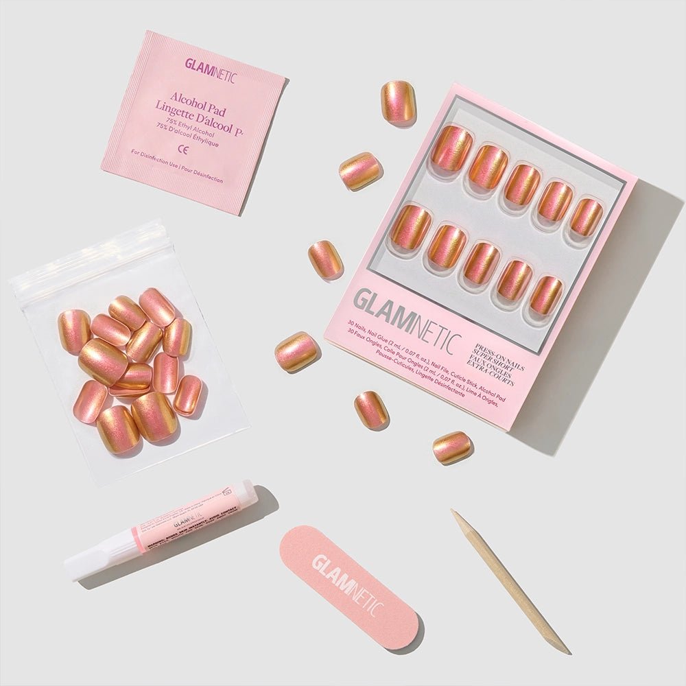 The Glamnetic Papaya Chrome set features pink and gold iridescent press-on nails, displayed with glue, an alcohol pad, nail file, cuticle stick, and extra nails on a light background. - Product image