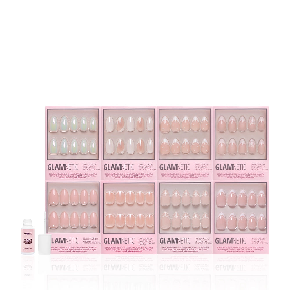 Eight boxes of glamnetic's Hopeless Romantic Bundle press-on nails in pale pink and nude shades, including a short almond set, are arranged in two rows with a small bottle of nail glue to the left. - Product image