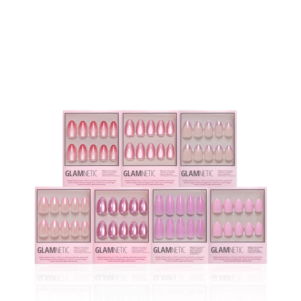 The glamnetic Soft Launch Bundle features seven boxes of press-on nails in pink and purple shades with chrome and almond styles, each displaying a unique glossy or shimmering look and arranged in two rows on a white background. - Product image