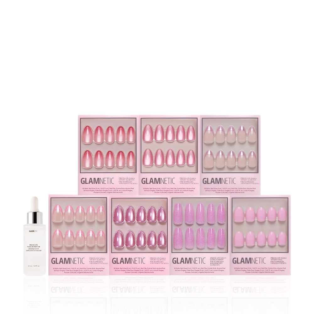 The glamnetic Soft Launch Bundle is displayed with six boxes of almond and pink press-on nails in two rows, plus a bottle of Glamnetic cuticle oil placed in front on the left. - Product image