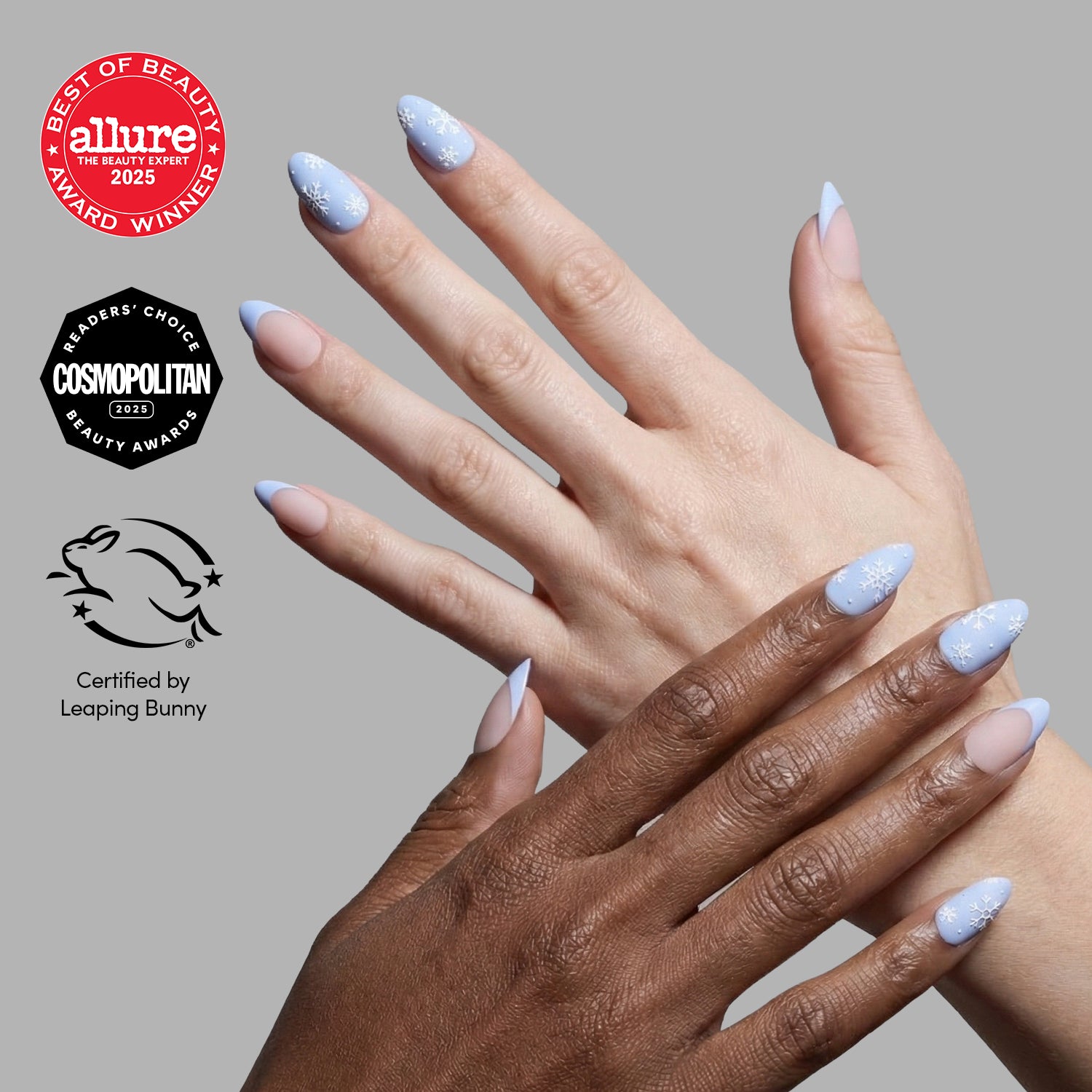 Two hands with long, matte almond nails in pastel blue and white "Snow Bunny" designs by glamnetic are shown against a gray background. Allure, Cosmopolitan, and Leaping Bunny award logos appear on the left.