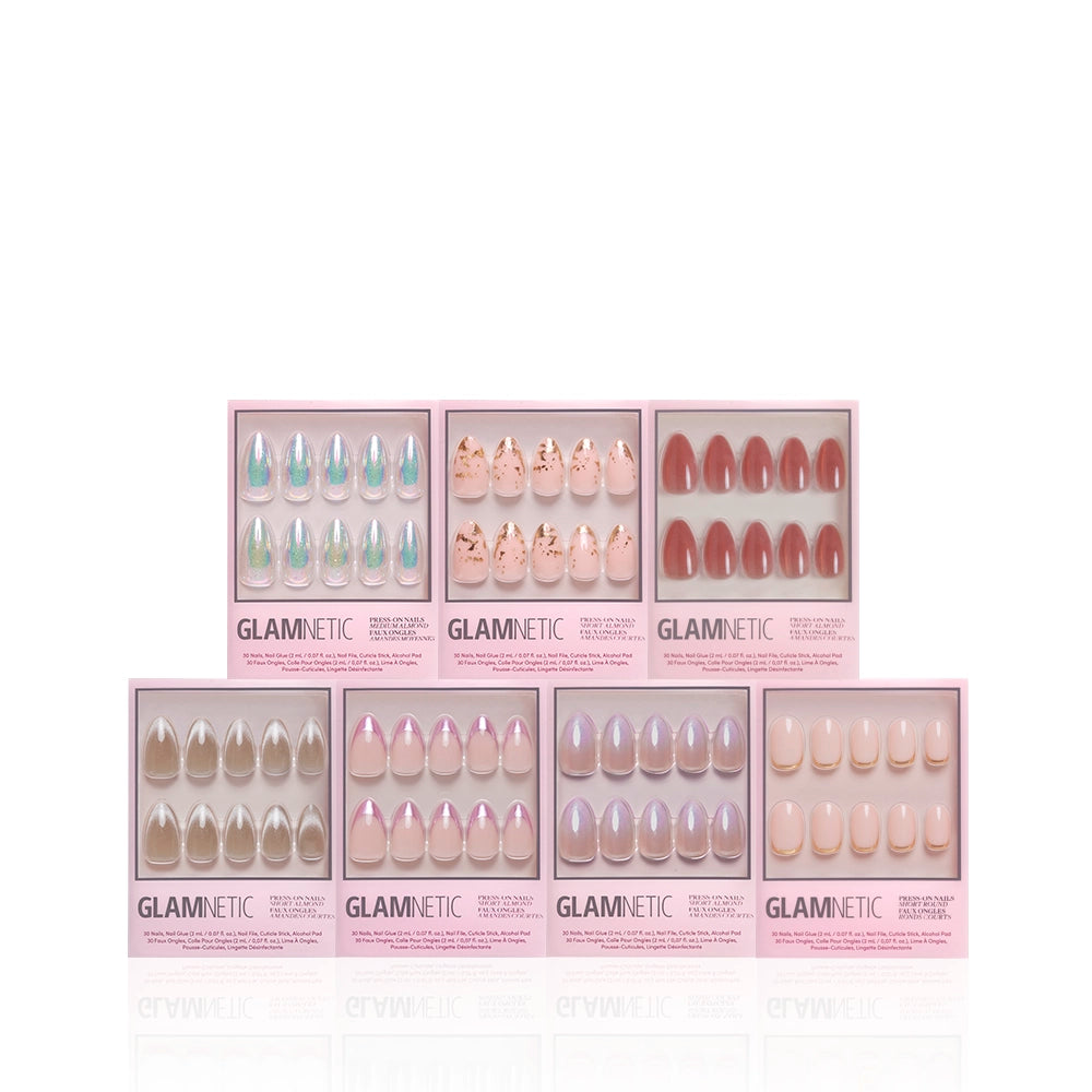 Seven boxes of glamnetic Glow On press-on nails, featuring almond-shaped sets in nude, pink, glitter, metallic, and patterned designs, are arranged in two rows against a white background. - Product image