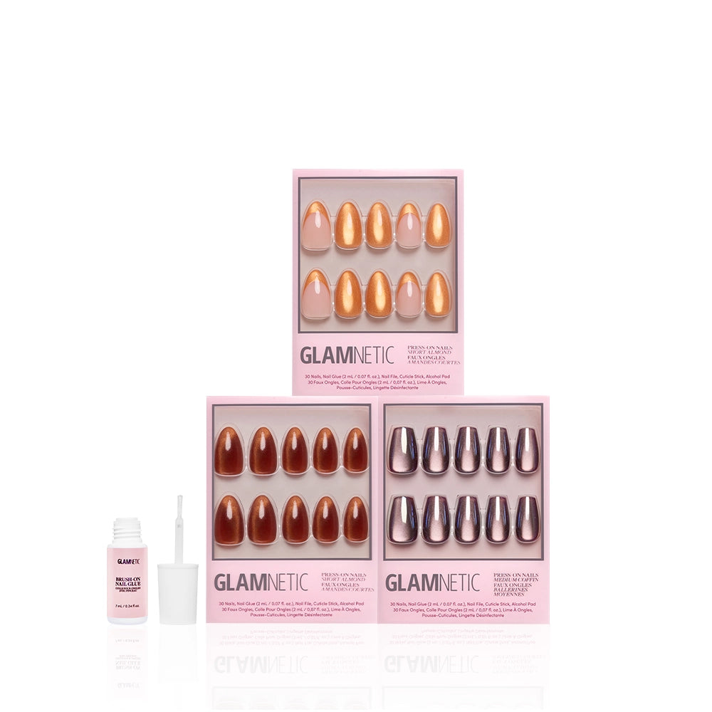 Three boxes of glamnetic La Vida Velvet press-on nails in assorted shades are stacked in a pyramid, with a bottle of nail glue and its applicator displayed in front, all set against a white background. - Product image