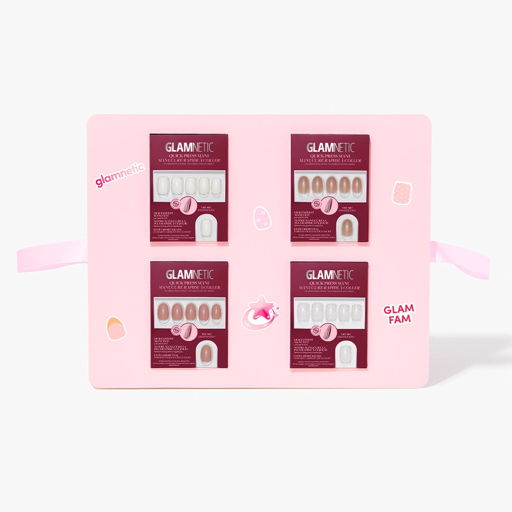 A pink glamnetic Quick Press Mani PR Box displays four sets of stick-on nails in neutral shades, each with separate packaging, decorative stickers, and the phrase "GLAM FAM" on the box. - Product image