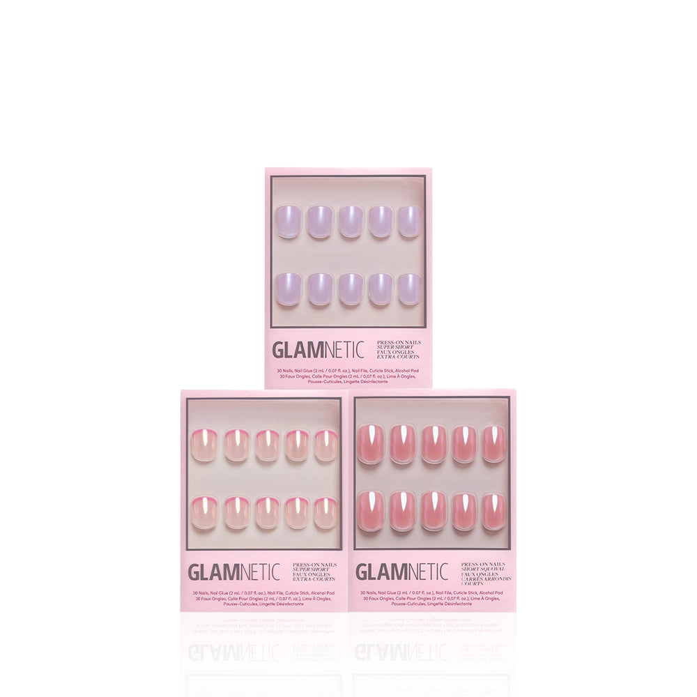 Three boxes of glamnetic The Short List press-on nails in pink packaging, featuring short squoval sets in lavender, sheer pink, and rose pink glazed shades, are stacked in a pyramid on a white background. - Product image