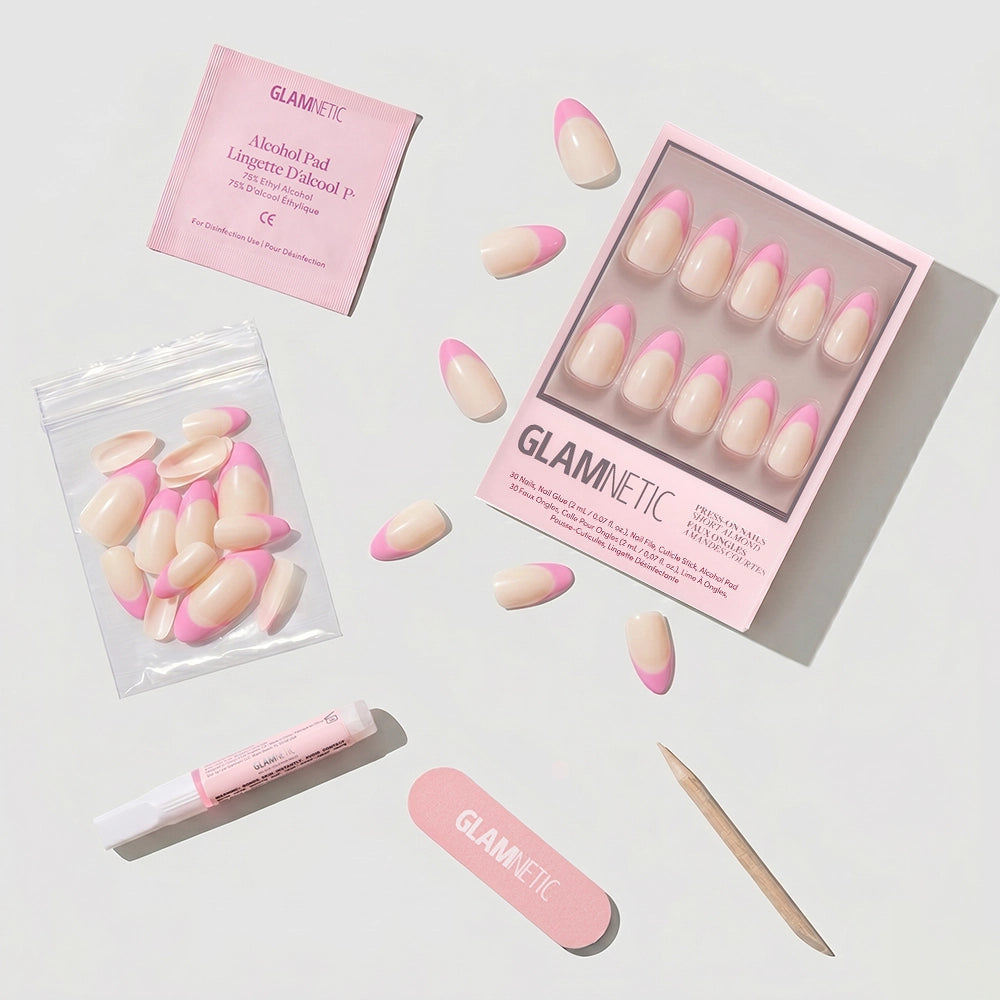 The glamnetic Bubble Gum Glaze short almond press-on nail set features glazed French tips and includes a box, scattered nails, alcohol pad, nail glue, nail file, cuticle stick, and resealable bag—neatly displayed on a light surface. - Product image